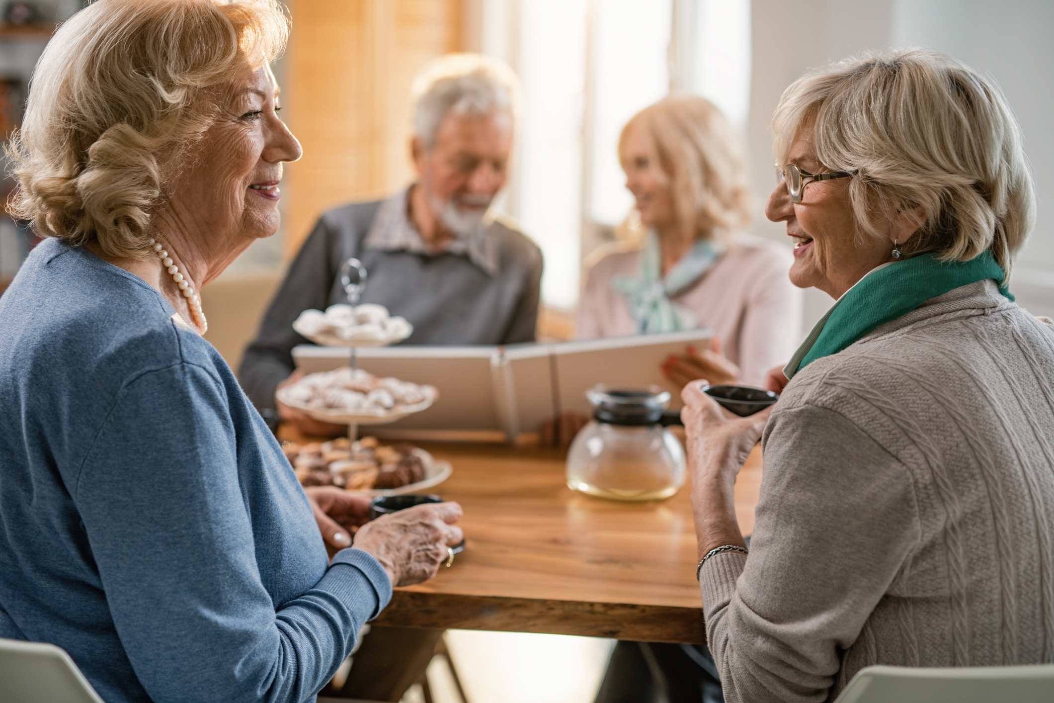 Seniors sitting around a table drinking coffee and chatting